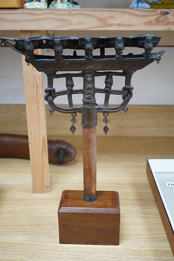 An 18th/19th century Indian Buddhist bronze oil lamp, on a later wood stand, 42.5cm high. Condition - fair